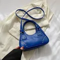 Borsa hobo blu reale con borchie dorate e tracolla abbinata su tessuto crema - Blu