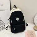 Detailansicht des Canvas-Rucksacks im Color-Block-Design mit Smiley und Seitenschnallen - Schwarz