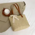 Beige woven straw tote bag with brown leather handles and a white lace bow accent - Brown