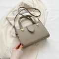 Minimalistische quadratische Umhängetasche aus taupefarbenem Leder mit Goldbeschlägen - Grau