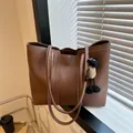 Detalle de bolso tote marrón con costuras blancas en contraste y colgante de peluche - 37*25.5*13 / Café con colgante