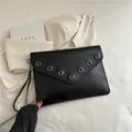 Pochette nera a busta con occhielli argentati e cinturino da polso abbinato - Nero