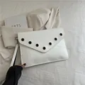 Pochette a busta bianca con occhielli in metallo nero e cinturino da polso chic - Bianco