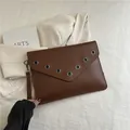 Pochette a busta marrone con occhielli in metallo argento e cinturino da polso - Marrone