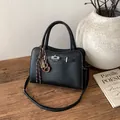 Elegant black lychee textured leather handbag with silver lock and tassel decoration - Black (With Pendant)