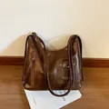 Retro brown leather tote bag with vintage texture and metallic details on white books - Brown