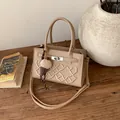 Stylish beige crossbody bag with GA embroidery and ice cream charm on a wooden desk - Khaki With Rabbit Pendant