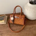 Brown faux leather crossbody bag with GA embroidery and crown detail on a wooden desk - Brown with Pendant