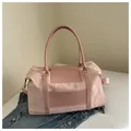 Détail macro du sac de voyage rose montrant le tissu gaufré et les poignées en PU lisse - Rose
