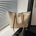 Minimalistische beige Shopper-Tasche mit braunen Lederriemen und Metalllogo auf Fensterbank - Weiß