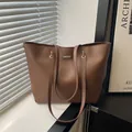 Braune Shopper-Tasche aus Leder mit goldener Schnalle in minimalistischem Raumlicht - Braun