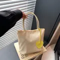 Minimalist cream nylon tote bag with a vibrant yellow heart charm and sleek handles - Light Yellow