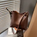 Dettaglio borsa a secchiello in pelle marrone scuro con tracolla annodata e oro metallo - Marrone