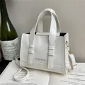 Borsa a mano vintage bianca con manici e tracolla regolabile su un libro aperto - Bianco