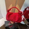 Vintage red faux suede handbag with knotted handle detail shown against a mirror - Burgundy