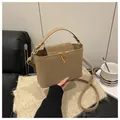 Detail van kaki emmertas met gouden V-sluiting en verstelbare riem op een bureau - Khaki