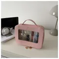 Detailed close-up of pink cosmetic bag with transparent window and gold zippers - Pink