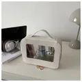 Macro view of cream vanity bag with transparent window and golden dual zippers - Off White