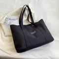 Minimalist black canvas tote bag with fashion label and wide straps on white fabric - Black