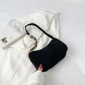 Detalle de bolso media luna de pana negra con cadena dorada sobre una chaqueta blanca - Negro