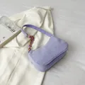 Primer plano de bolso baguette de pana lila con cadena acrílica sobre un fondo blanco - Morado