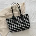 Classic black and white checkered tote bag with leather straps on a beige blazer - Black