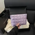 Hand holding a purple quilted makeup bag with metallic satin finish and zipper - Purple