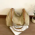 Grande borsa shopping kaki con manici marroni su una rivista per un look casual - Cachi