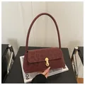 Close-up of burgundy leopard embossed shoulder bag with gold buckle on velvet texture - Red