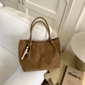 Brown suede leopard style tote bag with wooden bead charm on a white sofa backdrop - With Pendant / Brown