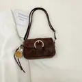 Minimalistische dunkelbraune Wildleder-Tasche mit Hufeisen-Schnalle und Baseball-Anhänger - Braun mit Anhänger