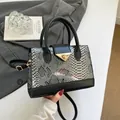 Fashionable handheld bag featuring black and grey snakeskin pattern with a gold metal buckle - Black