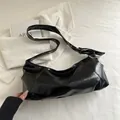 Minimalist black glossy faux leather shoulder bag with a stylish knotted strap detail - Black