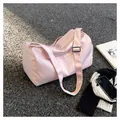 Detailed close-up of pink nylon travel bag with adjustable strap on outdoor ground - Pink