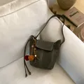 Sac seau minimaliste rétro en cuir gris avec pompon décoratif sur un canapé - Sans Pendentif / Vert