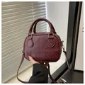Détail du sac à main bordeaux en cuir texturé avec embossage vintage et double poignée - Rouge