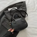 Mini black shell crossbody bag with embossed logo and gold hardware on white fabric - Black