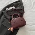 Retro burgundy shell bag with embossed letters and golden hardware on grey blazer - Red