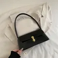 Glossy black baguette shoulder bag featuring a sleek golden metal clasp and slim strap - Black