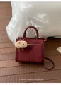 Detailed macro view of the dark burgundy suede leather tote with a beige plush mascot charm - Burgundy Red With Charm