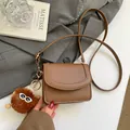 Brown pebbled leather mini crossbody bag featuring a cute furry charm and slim strap - With Pendant / Brown