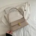 Elegant beige leather baguette shoulder bag with gold metal buckle on a white blazer - Khaki