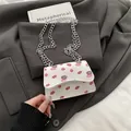 Weiße Mini-Umhängetasche mit Lippenstift-Print und silberner Kette auf grauem Anzug - Lippen Weiß