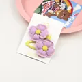 Détails de deux barrettes à fleurs en tissu violet avec coutures jaunes et cœur central - Violet