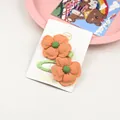 Détail de barrettes à fleurs en tissu orange faites à la main avec surpiqûres vertes - Orange