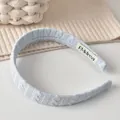 Bandeau tricoté bleu clair avec motif torsadé et étiquette de marque élégante - Serre-tête / Bleu Laiteux
