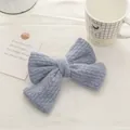 Detail of light blue knitted mohair double bow hair clip on cozy cream textile fabric - Creamy Blue