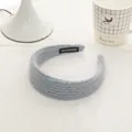 Detail of light blue chunky knit headband with a black handmade label on soft fabric - Milk Blue
