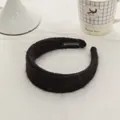 Detail of a thick black mohair knit headband with a handmade label on a white table - Black