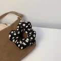 Gros plan d'un chouchou à pois noirs et blancs sur un sac en velours côtelé marron et bois - Noir Tacheté